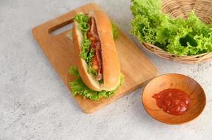 hotdog med sallad och tomat på en träskärbräda