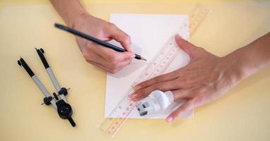 kvinna hand använder sig av en linjal med de penna framställning till dra och skiss på de tömma vit papper. foto