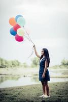 ung kvinna med färgglada ballonger i naturen foto