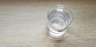 topp se eller platt lägga glas av kall vatten sätta på ljus brun eller grå trä- tabell för bakgrund med kopia Plats. förfriskning, dryck, objekt, klart och glänsande begrepp foto
