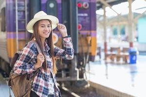 skön ung asiatisk kvinna väntar för tåg på tåg station, resa och semester begrepp. kinesisk turister. foto