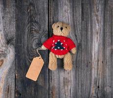 små brun gammal teddy Björn med en papper tom märka foto