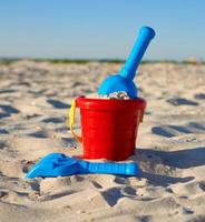 röd plast hink och blå räfsa, skyffel på de sand foto