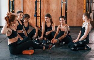 Sammanträde på golv. grupp av ung sportigt människor ha crossfit dag inomhus i Gym foto