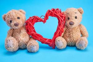 två små teddy björnar och en röd dekorativ korg- hjärta foto