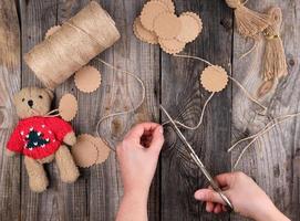 kvinna händer skära brun rep för taggar, leksak framställning bearbeta foto