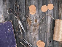 spole av brun rep, papper taggar och gammal sax på en grå trä- bakgrund foto