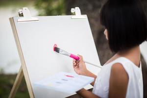 liten flickakonstnär som målar en bild i parken foto