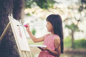 liten flickakonstnär som målar en bild i parken foto