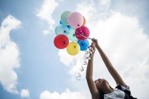 ung flicka som håller färgglada ballonger i naturen foto