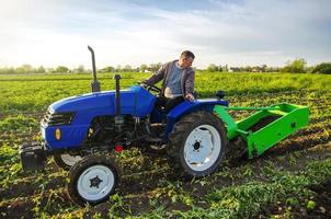 en jordbrukare på en traktor gräver potatisar med en grävare. de använda sig av av modern teknologi på de odla. fri människor från tung landa arbete. jordbruk och jordbruksmark. landsbygden. mat produktion foto