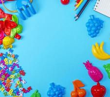 blå bakgrund med barns plast leksaker, pennor, ballonger och trä- brev foto