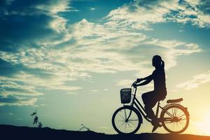 silhuett av en kvinna med en cykel och vacker himmel foto