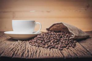kaffekopp med kaffebönor på ett träbord