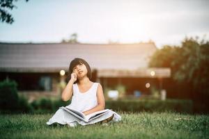 liten flicka som läser en bok i hennes husträdgård utanför