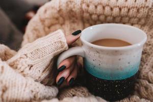 person som håller blå keramisk mugg med kaffe foto