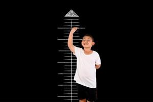ung pojke mäter sin höjd med tavlan foto