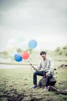 ung man som rymmer färgglada ballonger i naturen foto