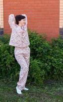 glad kvinna i Hem ha på sig pyjamas utomhus- tegel vägg bakgård bakgrund känslor - nattkläder och Hemma kläder begrepp foto