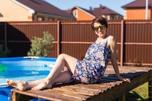porträtt av Söt ung kvinna i pyjamas Sammanträde nära uppblåsbar simning slå samman - sommar och Land liv begrepp foto