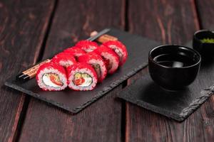 kalifornien sushi rulla med lax, avokado gurka och tobiko kaviar eras på svart styrelse närbild - japansk mat foto