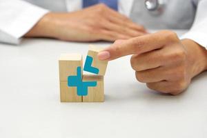 hand innehav en trä- blockera kub med sjukvård medicinsk ikon symbol. medicinsk och hälsa begrepp. foto