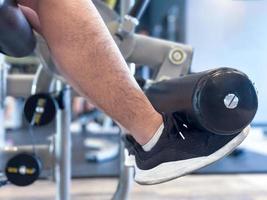fokus på de manlig ben, är använder sig av övning maskin till muskler tona i de ben. foto