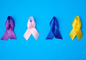 lila, gul, blå, rosa band i de form av en rosett, internationell symboler av sjukdomar foto
