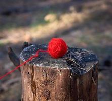 röd ull boll av garn för stickning liggande på en träd stubbe foto
