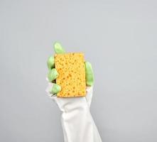 handskar hand innehar gul kök svamp foto