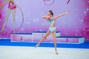 skön liten gymnast flicka på de matta på de konkurrens foto