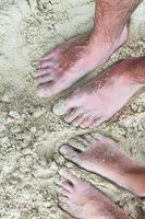 närbild fötter av en ung par på vit sand strand foto