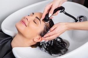 professionell frisör tvättning hår av ung kvinna i skönhet salong.. stänga upp av kvinnas hår i skönhet salong, frisyr begrepp foto