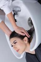professionell frisör tvättning hår av ung kvinna i skönhet salong. stänga upp av kvinnas hår i skönhet salong, frisyr begrepp foto