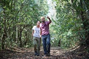 ungt attraktivt par som vandrar i skogen foto