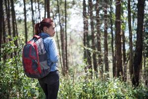 turist med ryggsäck som går genom skogen foto