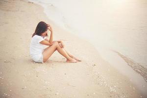 ung kvinna sitter på stranden foto