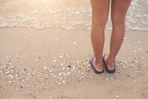 ung kvinna med flip-flop-sandaler på stranden foto