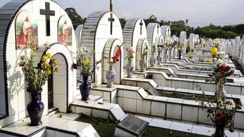 de offentlig kyrkogård innehåller identisk vit keramisk gravar med blommor. foto
