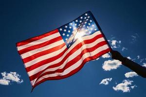 vinka USA flagga i hand mot blå himmel. foto