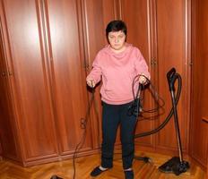 en medelålders kvinna samlar en Vakuum rengöringsmedel för hus rengöring. foto