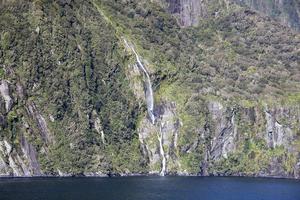 fjordland nationell parkera brant Strand med en vattenfall foto