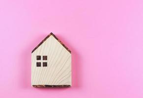 platt lägga av trä- modell hus på rosa bakgrund. foto
