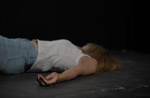 kvinna offer av våldsam brottslighet lögner på golv i mörk rum foto