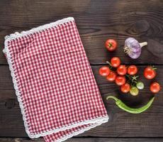 röd textil- kök handduk i en bur och färsk körsbär tomater foto