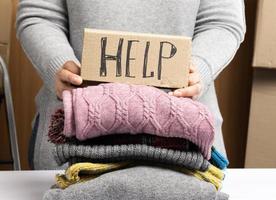 kvinna i en grå Tröja samlar kläder i en låda, begrepp av bistånd foto
