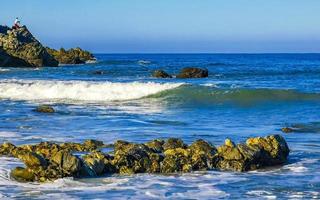 skön stenar klippor surfare vågor på strand puerto escondido Mexiko. foto