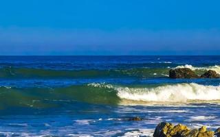 skön stenar klippor surfare vågor på strand puerto escondido Mexiko. foto