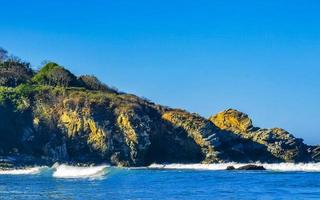 skön stenar klippor surfare vågor på strand puerto escondido Mexiko. foto