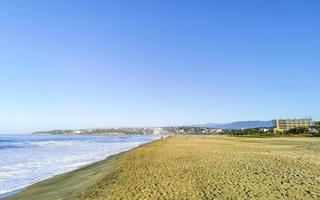 Sol strand sand människor vågor palmer i puerto escondido Mexiko. foto